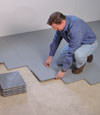 Contractors installing basement subfloor tiles and matting on a concrete basement floor in Hagerstown, Maryland